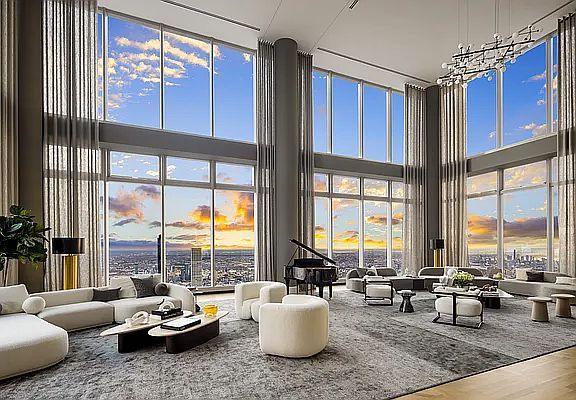 a large living room with high ceilings and floor to ceiling windows that overlook the city