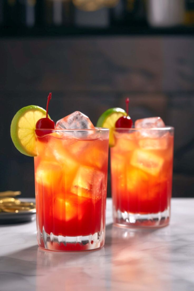 two glasses filled with drinks sitting on top of a white marble counter next to each other