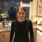 a woman standing in a kitchen next to a stove top oven and refrigerator freezer