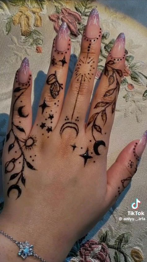 a woman's hand with tattoos on it and some stars in the sky above her