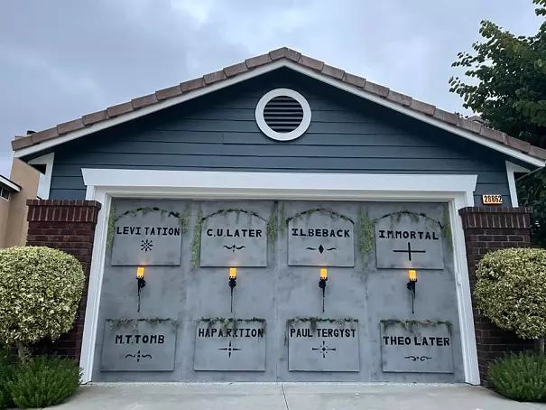 a garage that has some lights on the side of it and is decorated with plants