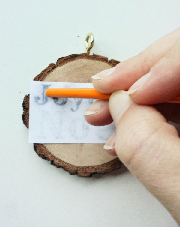 a person holding an orange pen near a piece of wood with a tag on it