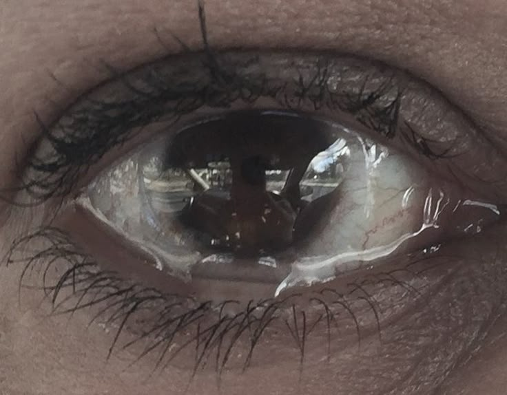 an extreme close up shot of someone's eye with the reflection of another person