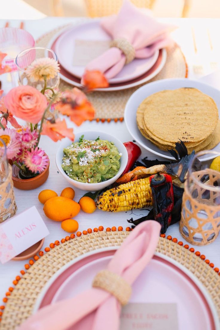 a table set with plates, napkins and flowers