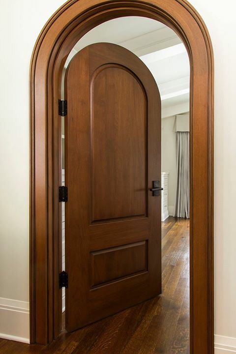 an arched wooden door in a white walled room with hardwood floors and hard wood flooring