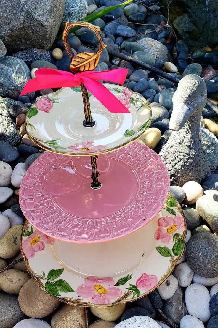 three plates stacked on top of each other with a pink ribbon around the edge and flowers on them