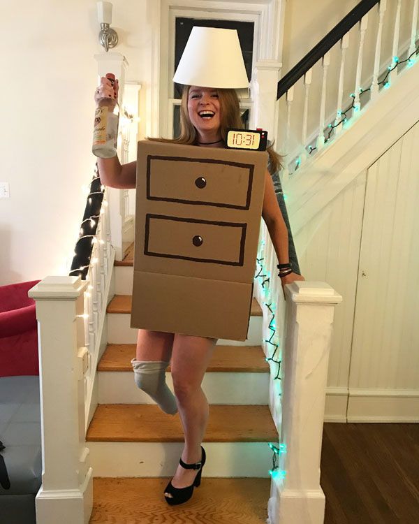 a woman in a cardboard box costume is walking down the stairs with a lamp on her head