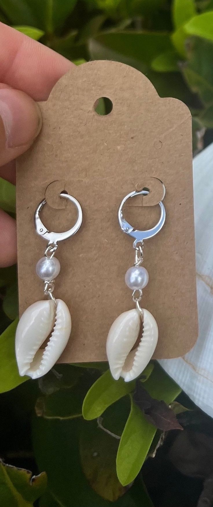 Handmade with real and authentic cowrie shells, these dangle earrings add an elegant and trendy look for any occasion. Choose gold or silver wiring and earring clasps.  Each seashell is meticulously handcrafted onto the earrings with a pearl colored bead and lever back clasps for a unique and organic element to your jewelry collection. Product Features: - Material: High-quality lever back clasp dangle earrings that are both durable and stylish, complemented by the authentic seashells for a disti Cowrie Jewelry, Seashell Earrings, Cowrie Shells, Saint Augustine, Cowrie Shell, Pearl Color, Jewelry Inspiration, Favorite Jewelry, Jewelry Earrings Dangle