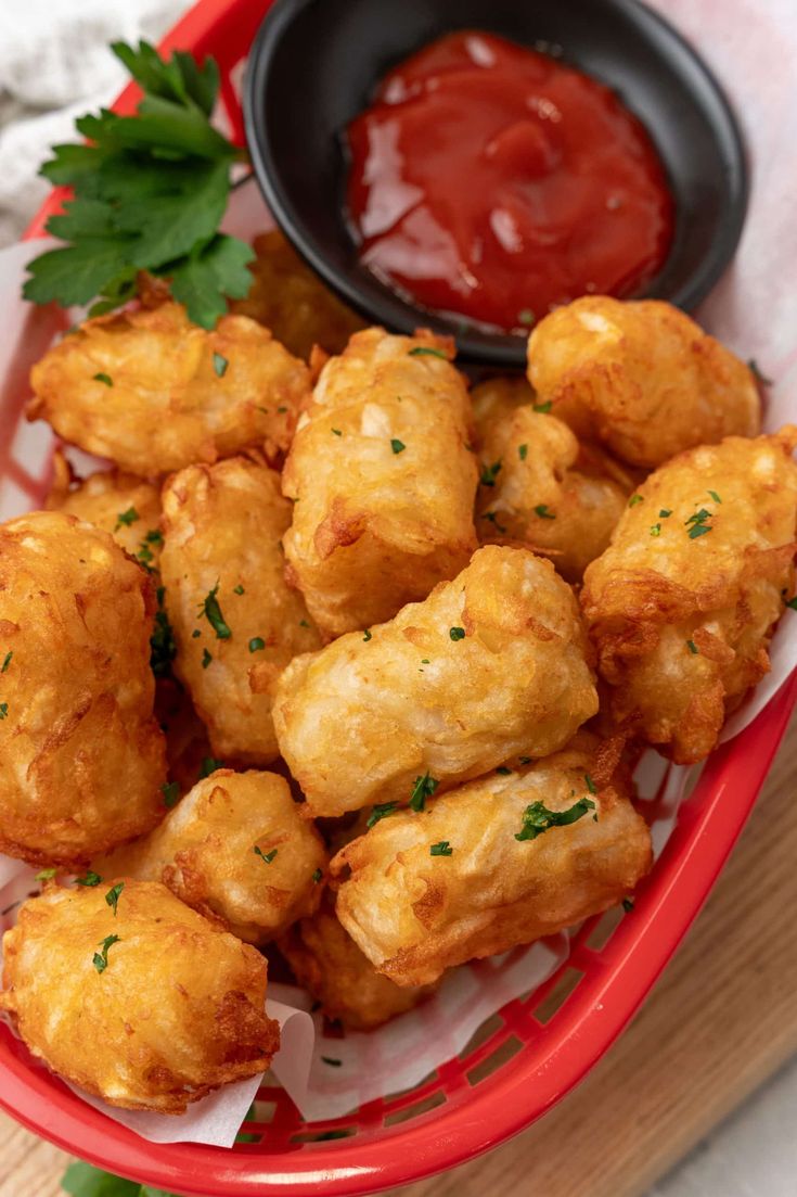 a basket filled with tater tots covered in ketchup and garnished with parsley