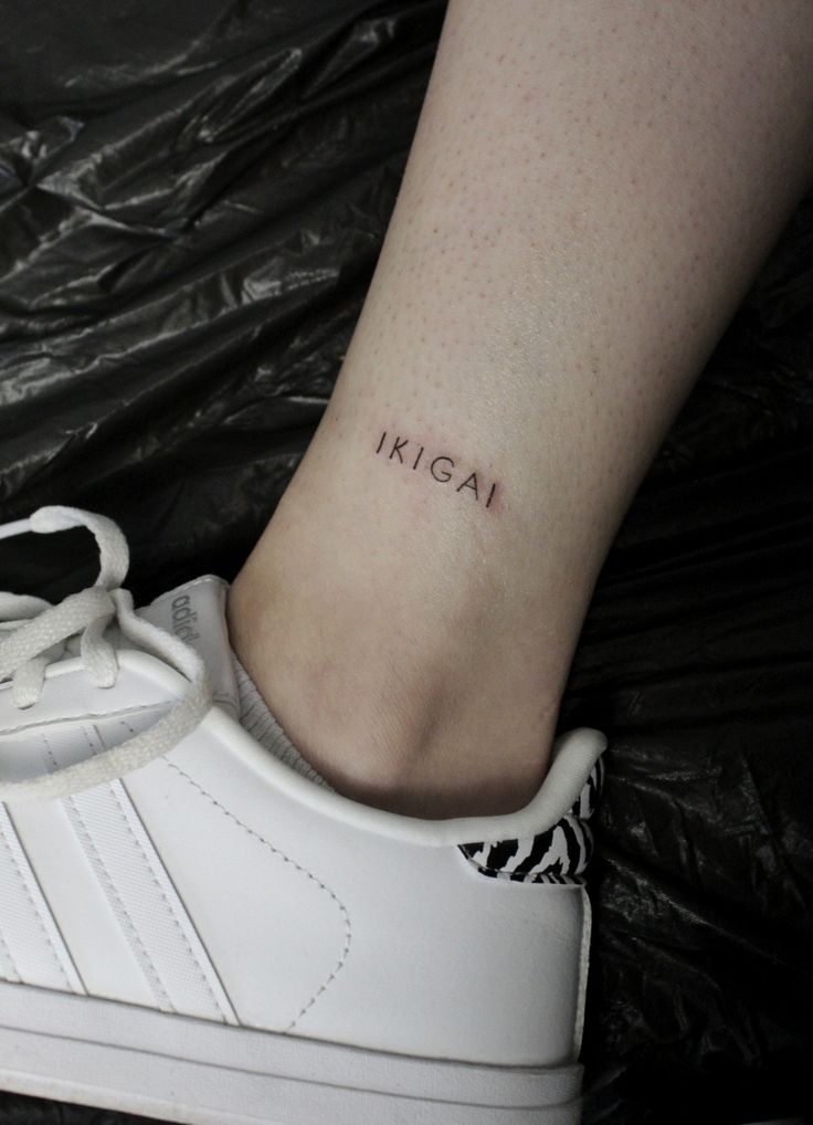 a woman's foot with a small tattoo on her left ankle, which reads kicai