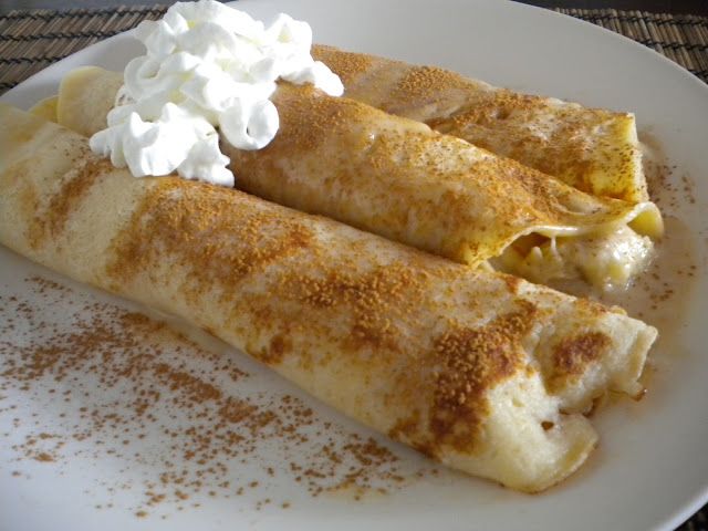 two crepes on a white plate topped with whipped cream