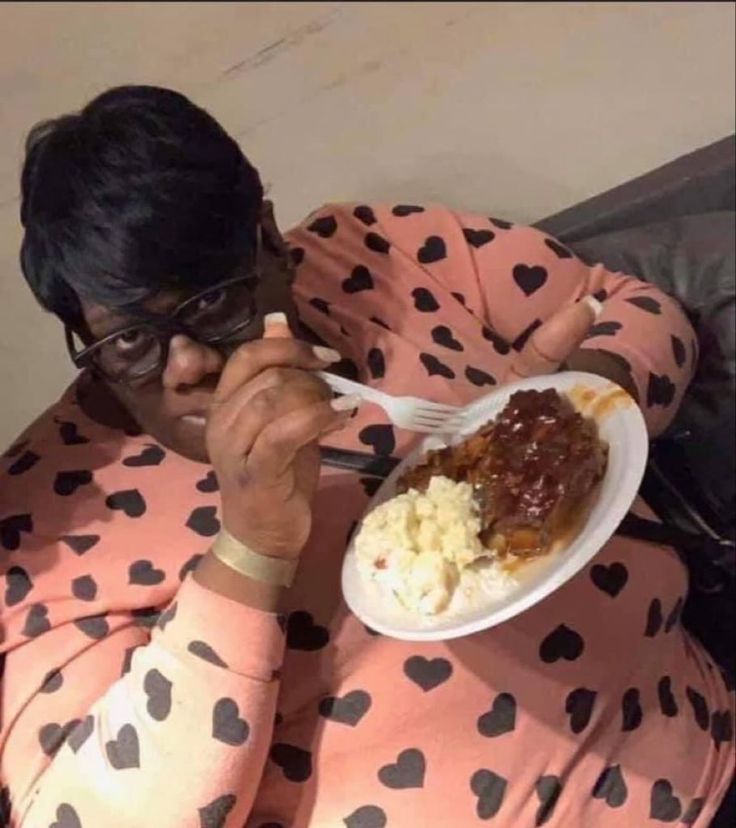 a man in pink pajamas eating food from a white plate