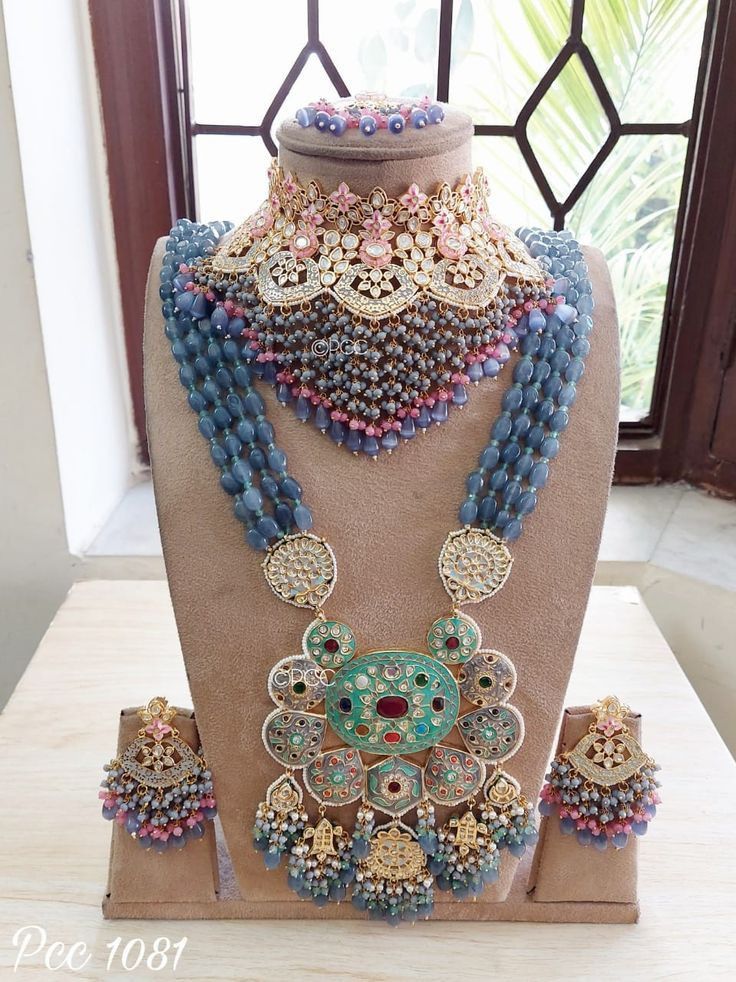 an elaborate necklace is displayed on a mannequin with other jewelry items in front of a window