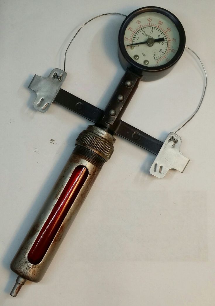 a pressure gauge attached to a pipe on a white surface with wires and plugs