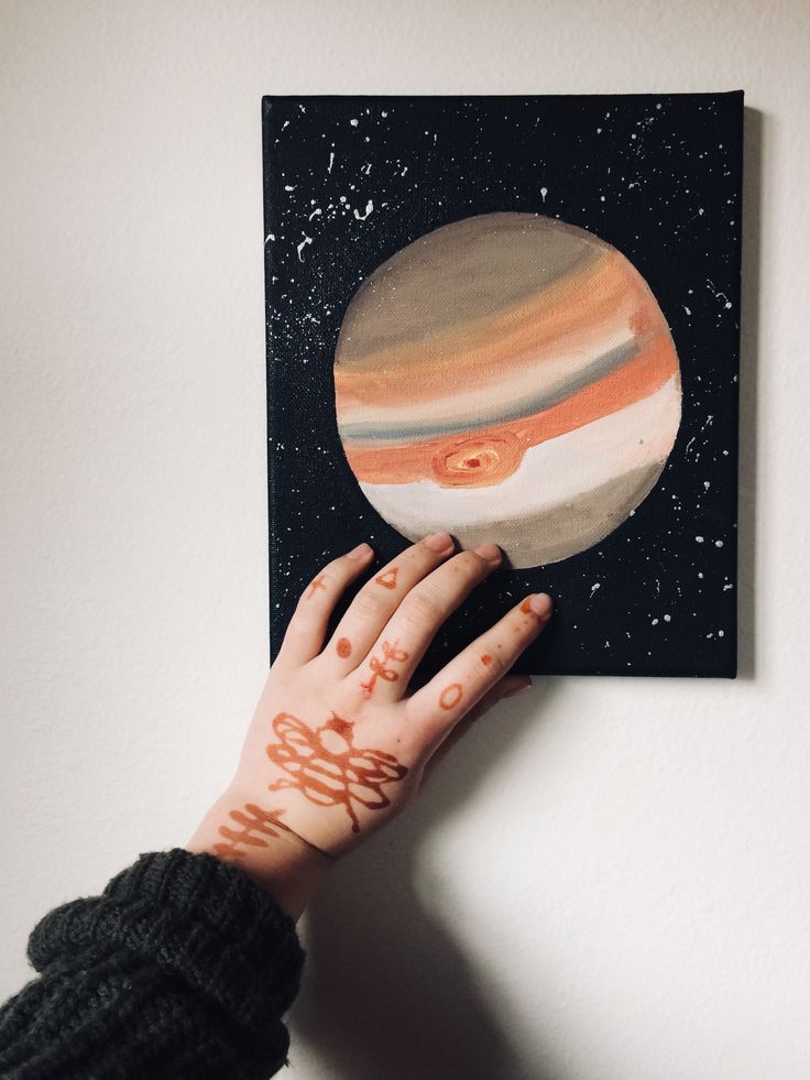 a person's hand reaching up to a painting on a wall with the planets painted on it