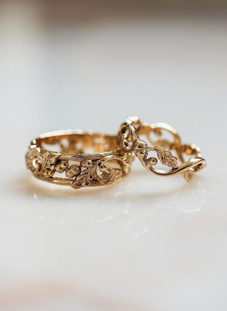 two gold wedding rings sitting on top of a table