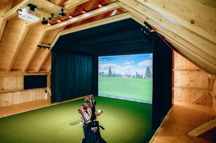 an indoor golf simulator is set up in a room with wood paneling and green carpet