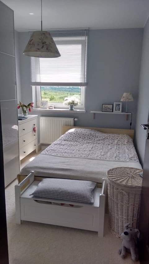 a white bed sitting under a window next to a night stand and dresser in a bedroom