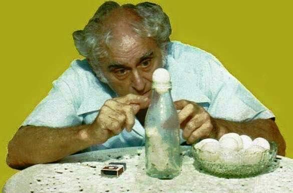 an old man sitting at a table with eggs in a bottle