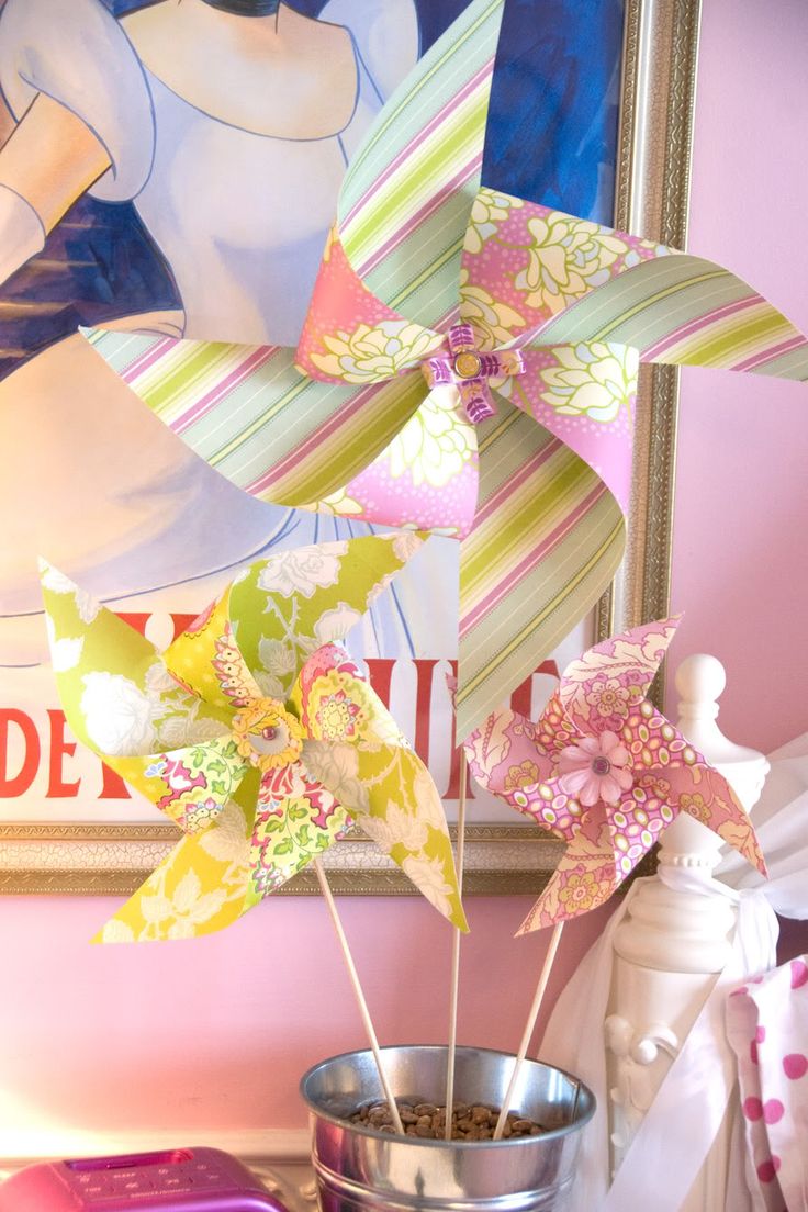 some pinwheels are sitting in a bucket on a table next to a painting