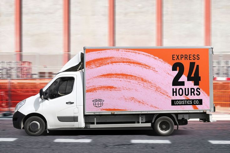 a delivery truck driving down the road with an orange sign on it's side