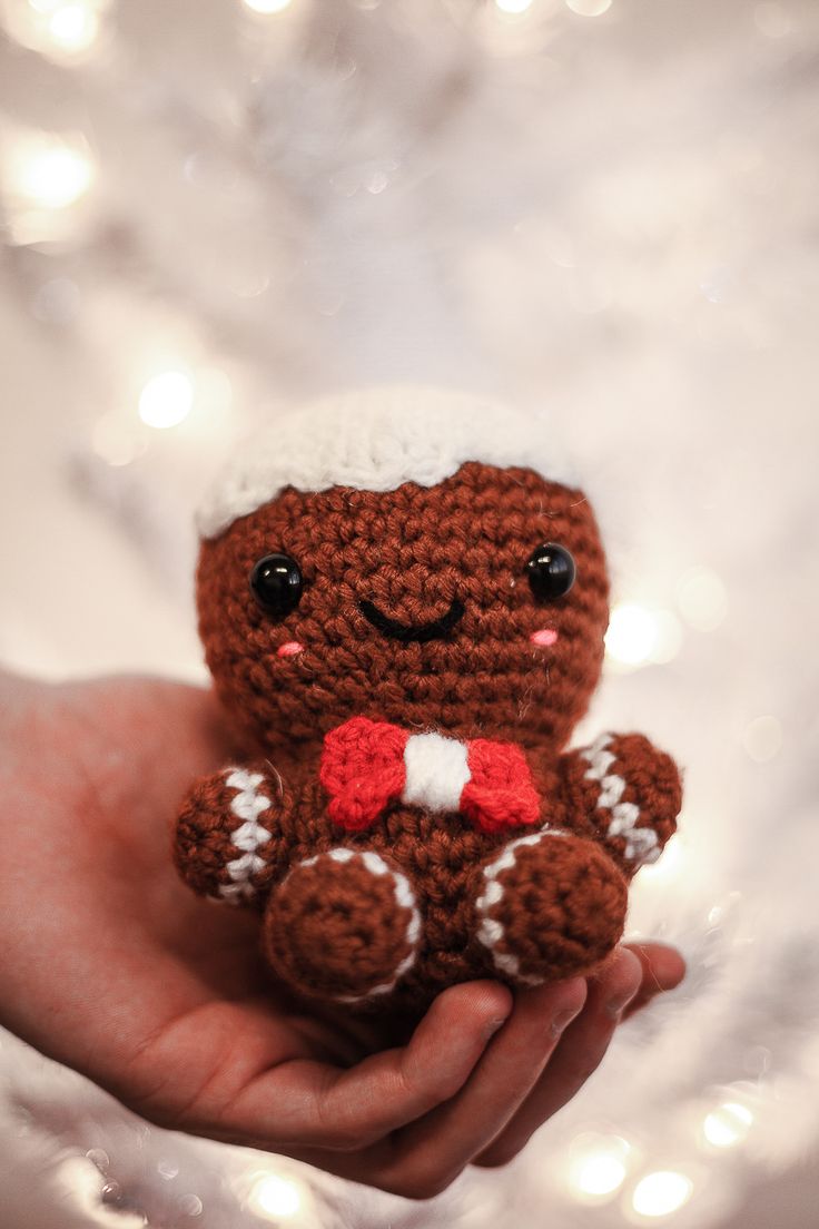 a hand holding a small crocheted teddy bear