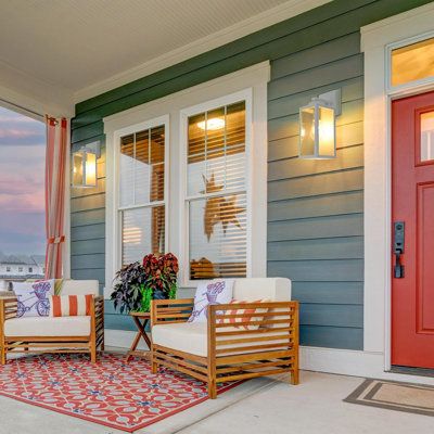 two wooden chairs sitting on top of a rug next to a red door and window