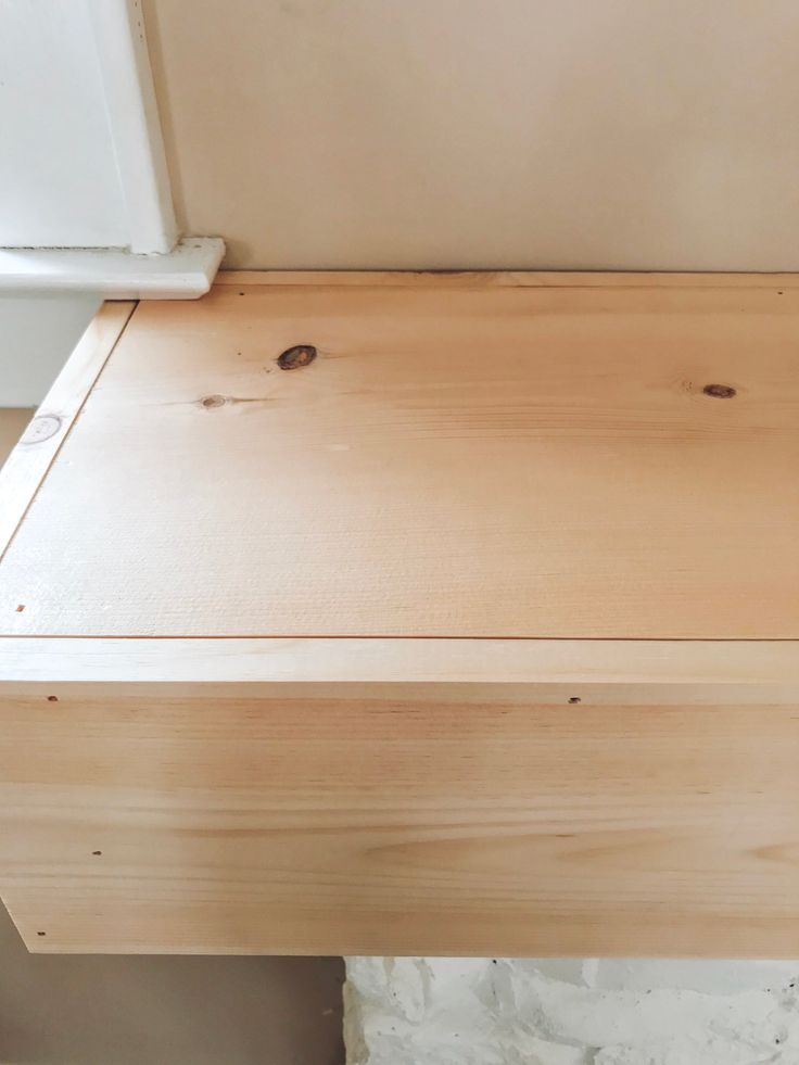 a piece of wood sitting on top of a wooden table next to a window sill