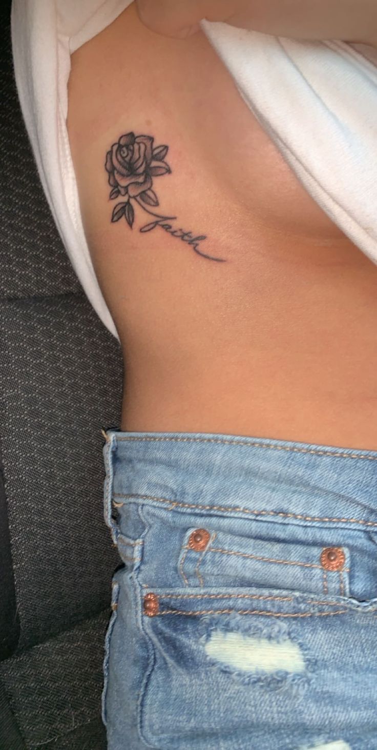 a woman's stomach with a rose tattoo on her left side ribcage