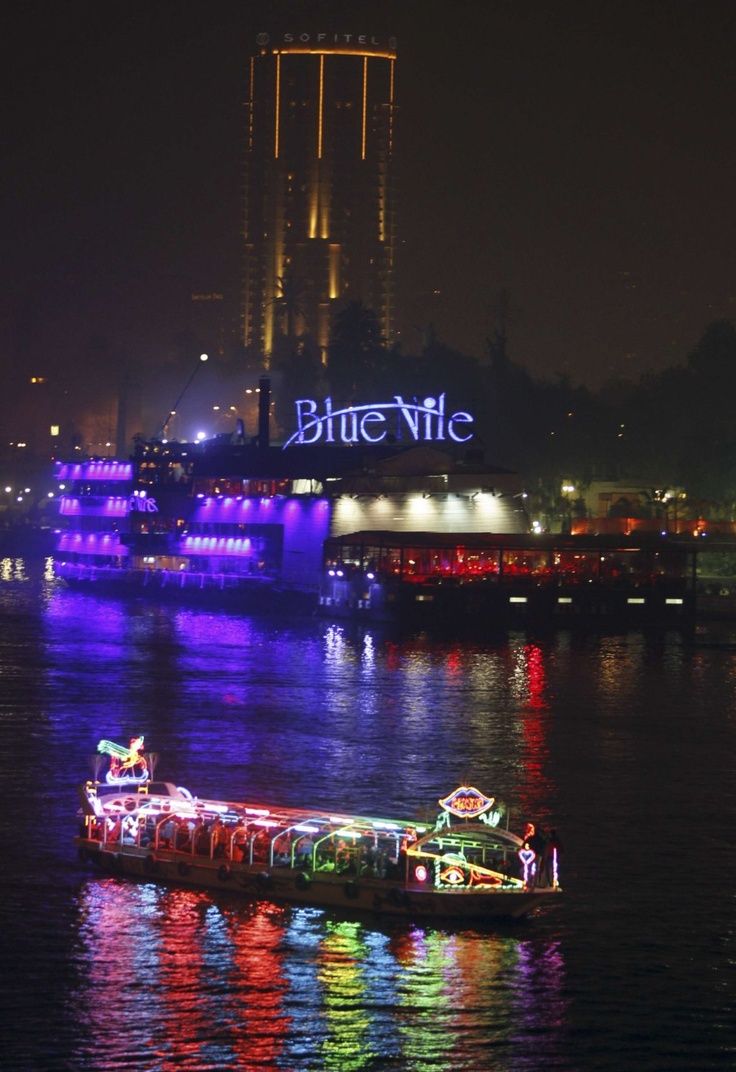 a boat with christmas lights on it is floating in the water near a city at night