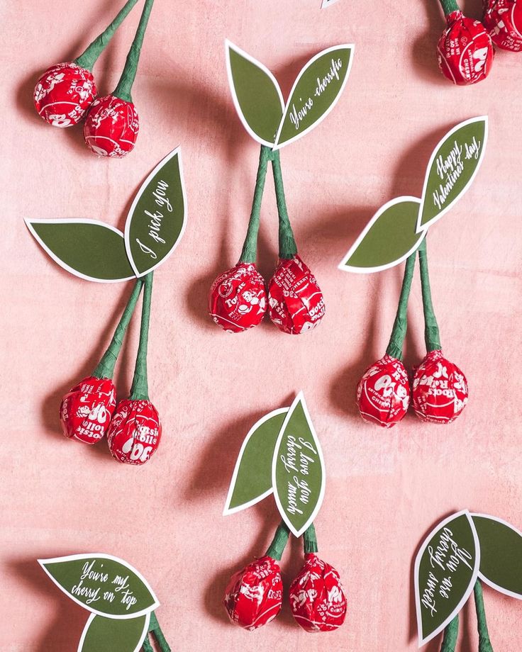 some red and green candies are on a pink surface with the words happy valentine's day written on them