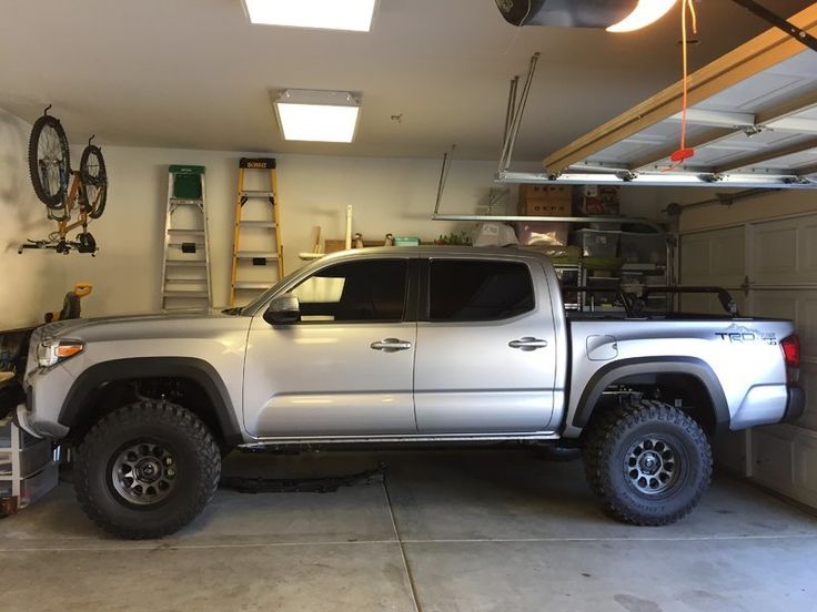 a white truck parked in a garage next to a wall mounted bike rack and ladder