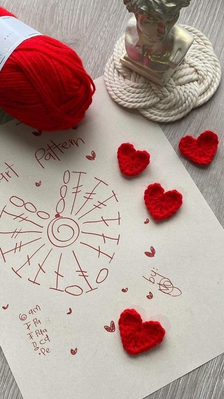 yarn and crochet hearts are on the table next to a piece of paper that says it is valentine's day