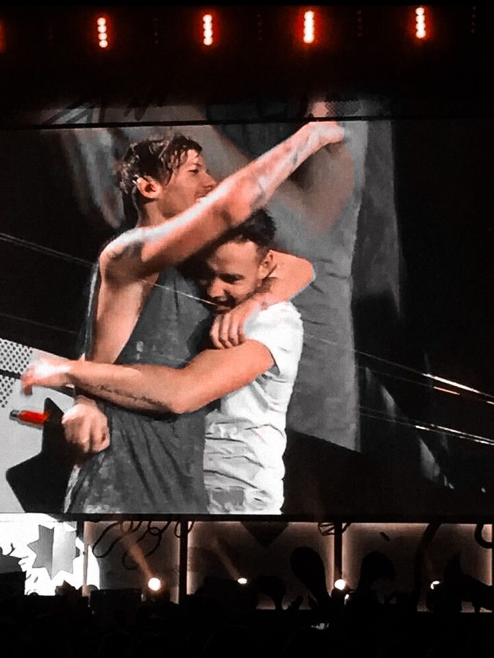 two men hugging each other on stage with lights in the backgroung behind them