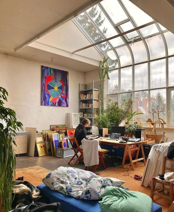 a room filled with furniture and lots of windows next to a wall covered in books