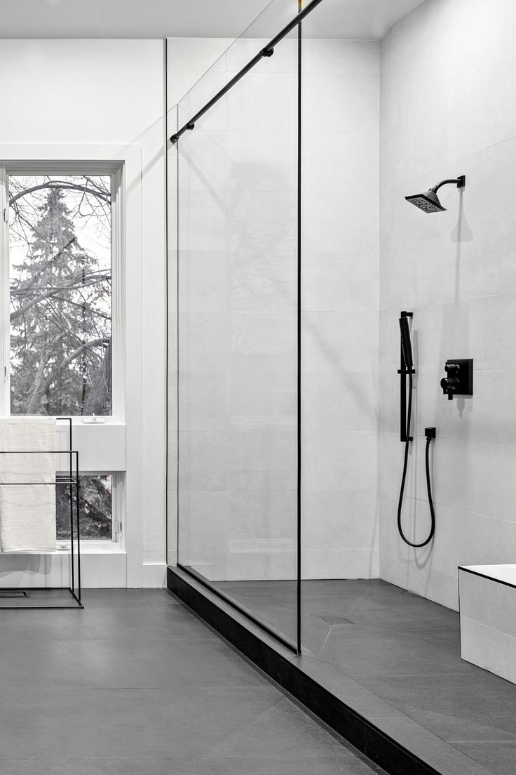 a bathroom with a large glass shower door and black faucet on the wall