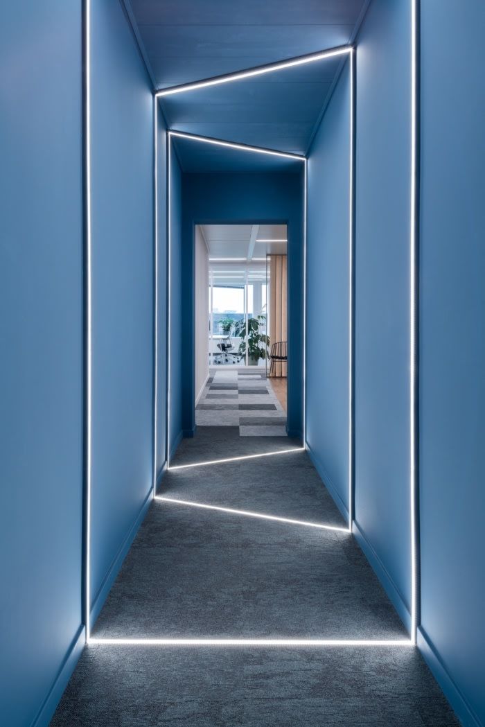 an empty hallway with blue walls and lights on either side, leading to a living room