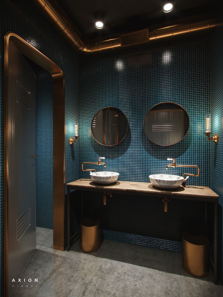 two sinks and mirrors in a bathroom with blue tiles on the walls, along with gold faucets