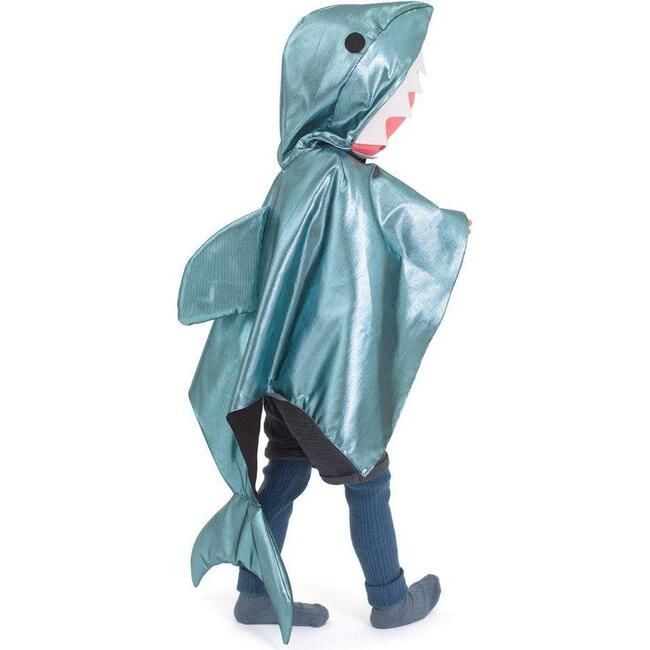 a little boy wearing a shark costume with his mouth open and tongue out, standing in front of a white background