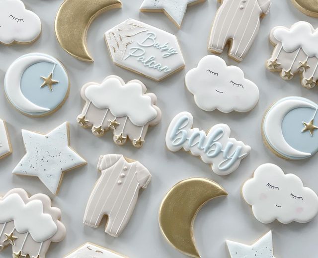 baby cookies decorated with white and gold icing, stars, moon, and clouds