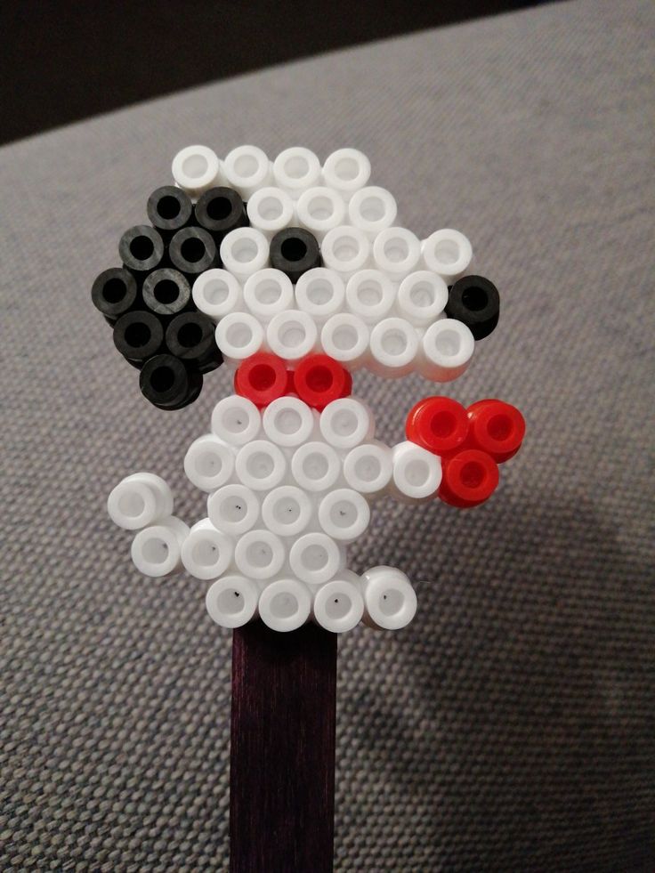 a sheep made out of legos sitting on top of a wooden stick with red and white buttons