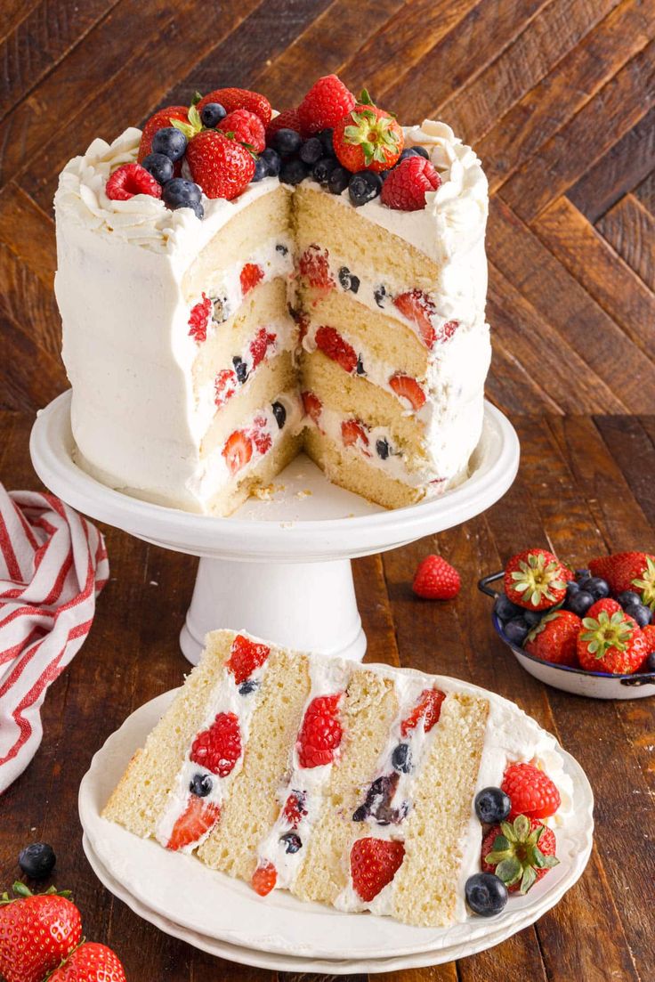 a triple layer cake with strawberries and blueberries on top is cut in half