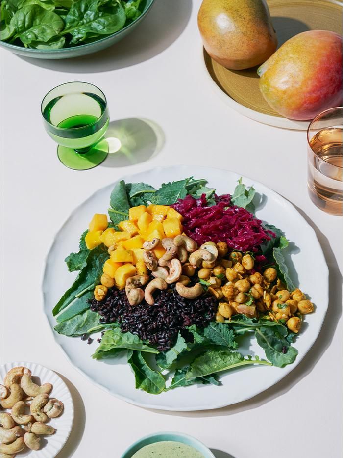 a white plate topped with lots of food next to bowls of fruit and veggies