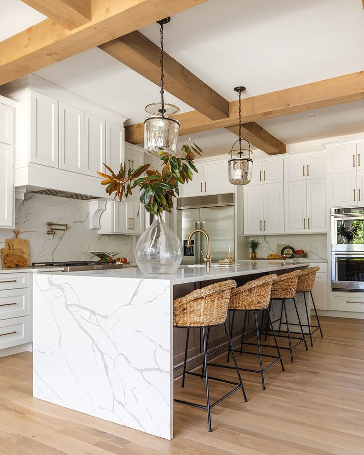 a large kitchen with white cabinets and marble counter tops, an island in the middle