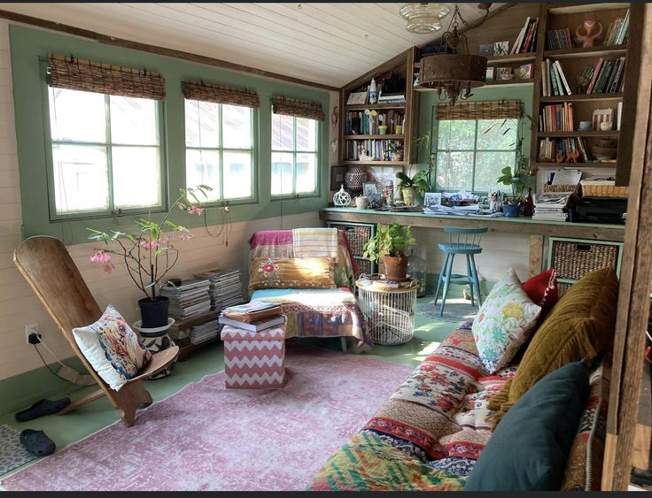 a living room filled with lots of furniture and bookshelves on the wall next to windows