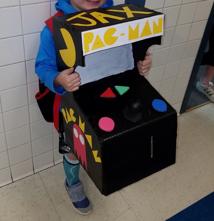 a young boy holding up a cardboard pac - man costume