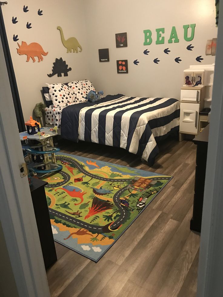 a room with a bed, rug and dinosaur wall decals on the walls in it