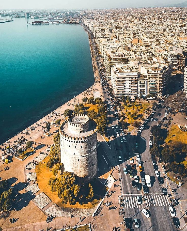 an aerial view of the city and its surrounding waterfront area with cars parked on the road