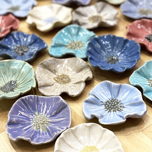 there are many flower shaped dishes on the table together, all in different colors and sizes