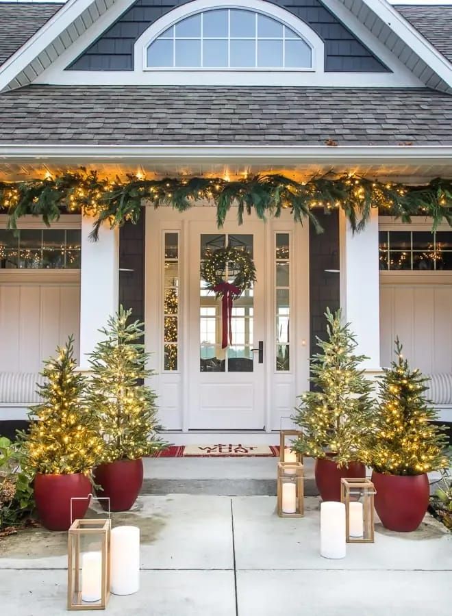 the front porch is decorated for christmas with candles and evergreen garlands on either side